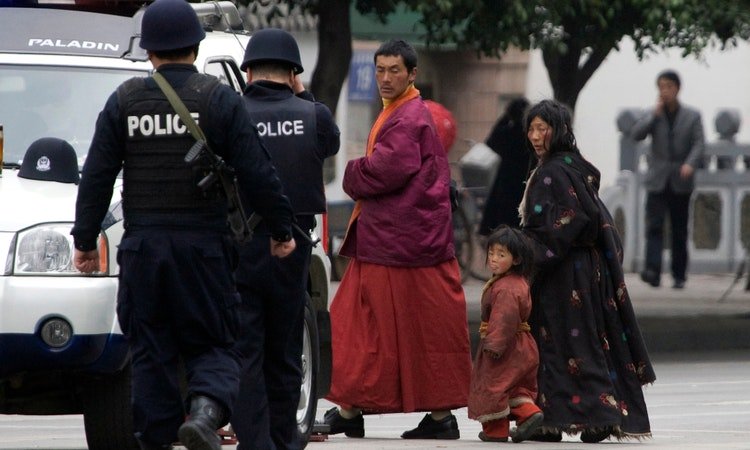 Police patrols passes by a Tibetan family in occupied-Tibet. Photo-Thenewlensinternational
