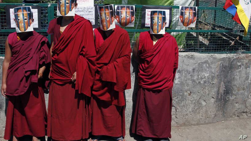 Tibetan monks in exile wear masks depicting the 11th Panchen Lama (Photo courtesy- VOA)