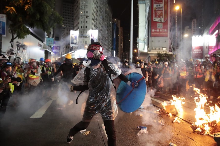A protestor in Hong Kong throws back a tear gas shell, back in August 2019 (AP)